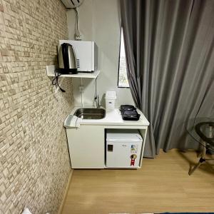 a small kitchen with a sink and a microwave at Loft Lux SM Chapecó - Amplo e aconchegante! in Chapecó +2 photos