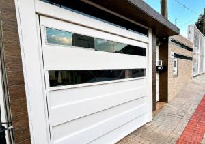 a white garage door on a house at Loft Lux SM Chapecó - Amplo e aconchegante! in Chapecó