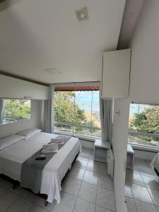 a bedroom with a large bed and large windows at Pousada Caravelas in Guarapari +82 photos