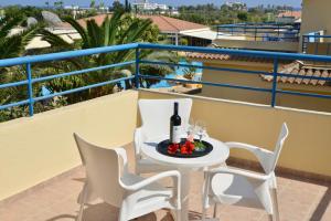 a table and chairs on a balcony with a bottle of wine at Makronisos Village in Ayia Napa
