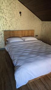 a large bed with white sheets and a wooden headboard at Arcadia Family Vacation House in Çilǝgir