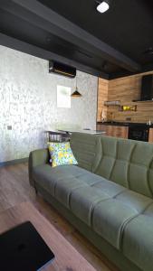 a green couch in a living room with a kitchen at Arcadia Family Vacation House in Çilǝgir