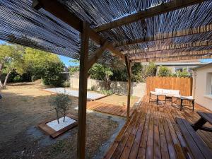 a wooden deck with a pergola with a table and bench at CAEN ça repose ! in Caen