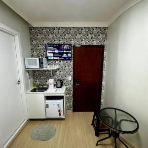 a small kitchen with a microwave and a door at Loft Lux SM Chapecó com excelente localização! in Chapecó