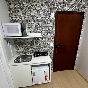 a small kitchen with a sink and a microwave at Loft Lux SM Chapecó com excelente localização! in Chapecó +3 photos