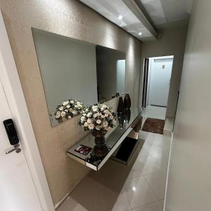 a bathroom with a mirror and a vase of flowers at Loft Lux SM Chapecó com excelente localização! in Chapecó