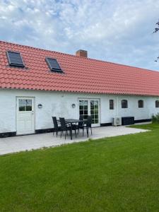 a table and chairs in front of a building with a red roof at Uggerhøjvej Gårdhygge in Hjørring