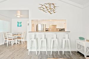 a white kitchen with a bar with white stools at Balboa Duplex in Newport Beach