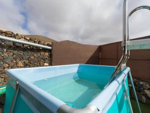 a blue hot tub in front of a stone wall at La Maxada Luz Maria in El Cotillo