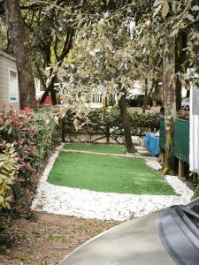 a yard with green grass and trees and a bench at Tiny house in Saint-Brévin-lʼOcéan