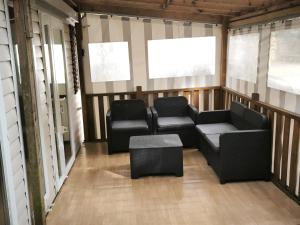 a screened in porch with two chairs and a couch at Tiny house in Saint-Brévin-lʼOcéan