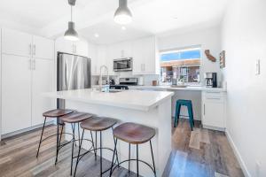 a kitchen with white cabinets and a counter with stools at Aloha-Howdy Surf Gateway in San Clemente