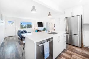 a kitchen with white cabinets and a stainless steel refrigerator at Aloha-Howdy Surf Gateway in San Clemente