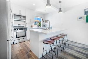 a white kitchen with stools at a kitchen counter at Aloha-Howdy Surf Gateway in San Clemente