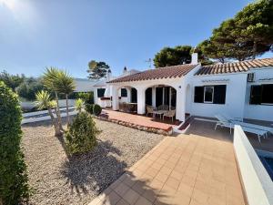 a white house with a patio and a yard at Villa Gabriela - piscine privée proche Punta Prima in Punta Prima
