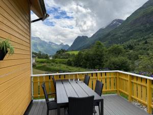 a wooden table and chairs on a deck with mountains at Naustvoll in Olden