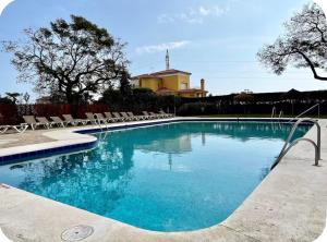 a swimming pool with chairs and a house in the background at Atalaya Green Nest in Estepona