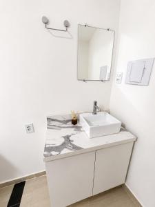 a white bathroom with a sink and a mirror at Manaira Suite 01 in João Pessoa