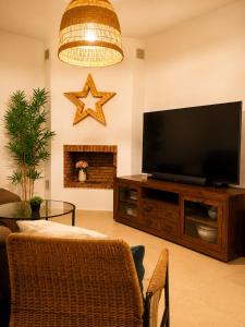 a living room with a flat screen tv on a entertainment center at Casa familiar con patio privado y piscina comunitaria cerca de la playa in Málaga