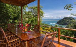 a wooden table and chairs on a deck with a view of the ocean at Casa Pura Paz in Puntarenas