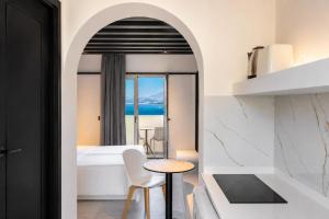 a bedroom with a bed and a table and a view of the ocean at Veneto Sea View Apartments in Stalís