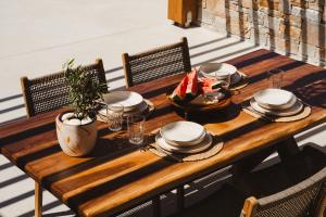 a wooden table with plates and dishes on it at Stone Waves Αpartments & Villas in Agios Arsenios