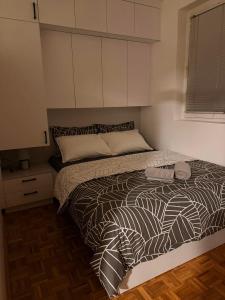 a bedroom with a bed with a black and white comforter at Apartman Centar, Modrica in Modriča