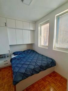 a small bedroom with a bed and two windows at Apartman Centar, Modrica in Modriča
