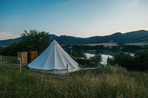 a white tent in a field next to a lake at Zálesie Glamping in Kostolná Ves