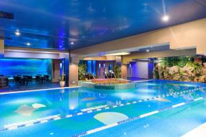 a large swimming pool in a house with an aquarium at Ariana Deluxe Suites in Bucharest