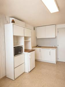 an empty kitchen with white cabinets and a microwave at Petit Biscuit - Wi-Fi - Kitchen - AC - Parking in Lido di Camaiore