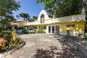 an exterior view of a yellow house with a driveway at Quinta dos Canais in Setúbal