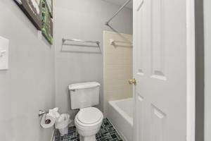 a white bathroom with a toilet and a bath tub at Stay at Cypress Cottage in Charleston