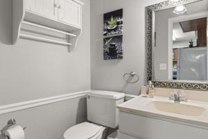 a bathroom with a toilet and a sink and a mirror at Stay at Cypress Cottage in Charleston