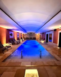 a large swimming pool in a building with a ceiling at Auberge de Cassagne & Spa in Le Pontet