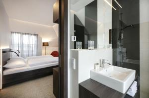 a bathroom with a sink and a bed at Hotel Spitzerberg by b-smart in Hundsheim