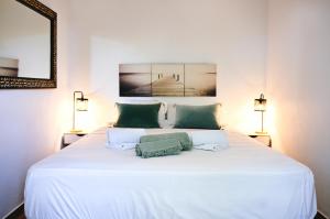 a white bed with two green pillows on it at l'Alzelle Plage in Biguglia