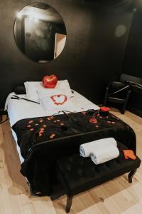 a bedroom with a bed with a table with towels at La Maison Coquine Love Room Balnéo in Béthune