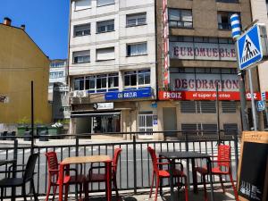 a group of chairs and tables in front of a building at CH Arzúa Pilgrim Hostel in Arzúa