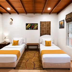 two beds in a room with white walls and wooden ceilings at Villa Lunka in Nuwara Eliya