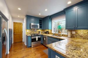 a blue kitchen with marble counter tops and blue cabinets at Dune Delight in Arroyo Grande +16 photos