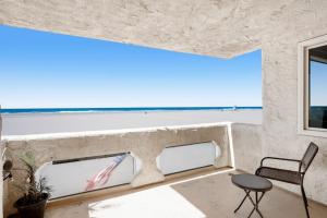 a room with two windows and a chair and the ocean at Sandcastle by the Sea in Oxnard