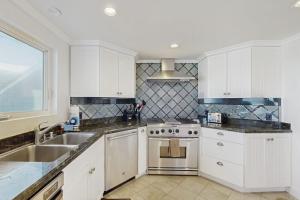 a kitchen with white cabinets and a sink and a stove at Savor the View in Oxnard +20 photos
