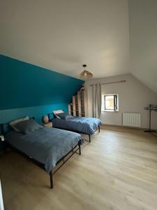 two beds in a room with a blue wall at Gîte Le Valeix in Neuvic