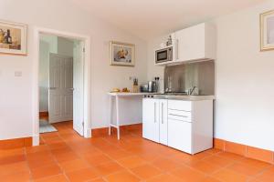 a kitchen with white cabinets and a orange tile floor at Quarry View Studio in Shrewsbury with Parking in Shrewsbury