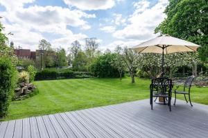 a wooden deck with a table and an umbrella at Quarry View Studio in Shrewsbury with Parking in Shrewsbury