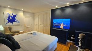 a bedroom with a bed and a flat screen tv at LÚA Cies Room in Oya