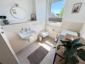 a bathroom with a sink and a toilet and a window at RegioStyle Gemütliche Wohnung im Schaalseepark! in Zarrentin +16 photos