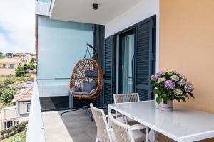 a balcony with a table and chairs and a swing at Canhas Ocean View in Ponta do Sol