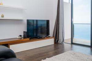 a living room with a flat screen tv on a entertainment center at Canhas Ocean View in Ponta do Sol
